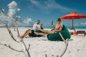 um homem e uma mulher sentados num limbo insuflável na praia em Siyam World Maldives - 24-Hour Premium All-inclusive with Free Transfer em Dhigurah