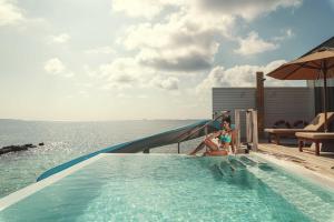 a young girl sitting on a slide in a swimming pool at Siyam World Maldives - 24-Hour Premium All-inclusive with Free Transfer in Dhigurah