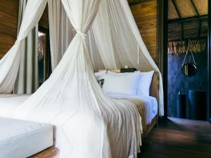 a bedroom with a canopy bed with white sheets at ONAYA Bali Resort - Adults Only in Uluwatu