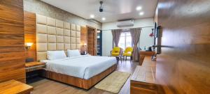 une chambre d'hôtel avec un lit, une table et des chaises dans l'établissement ROYAL CLIFF HOTEL & RESORTS, à Nagpur