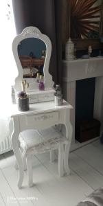 um toucador branco com um espelho e um banco em Chambre Bounty cuisine privée, salle d'eau, terrasse, garage em Olliergues