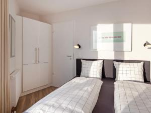 2 Betten in einem Schlafzimmer mit weißen Schränken in der Unterkunft MeerZeit Stilvolles Apartment am Meer, Wendtorf in Wendtorf