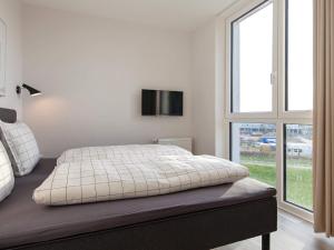 a white bedroom with a bed and a tv on the wall at Apartment Wendtorf XVI in Wendtorf