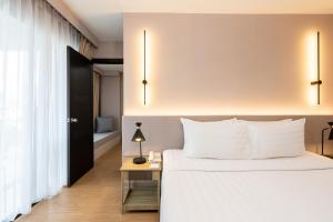 a bedroom with a bed and a table with a lamp at Aster Hotel and Residence by At Mind in Pattaya