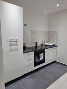 una cocina con armarios blancos y horno negro en LA DOLCE VITA, en Oyonnax