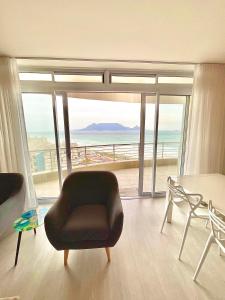 a living room with a chair and a view of the ocean at 706 Portico in Cape Town