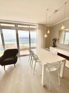 ein Wohnzimmer mit einem weißen Tisch, Stühlen und Meerblick in der Unterkunft 706 Portico in Kapstadt