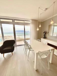 a living room with a white table and chairs and the ocean at 706 Portico in Cape Town