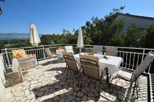 un patio con mesa, sillas y sombrillas en Apartments Blazevic, en Omišalj