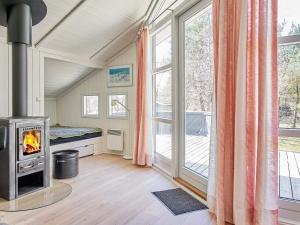 a living room with a fireplace and a large window at Holiday home Aakirkeby XIV in Vester Sømarken