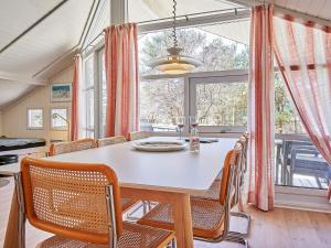 een eetkamer met een tafel en stoelen en een groot raam bij Holiday home Aakirkeby XIV in Vester Sømarken