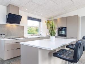 a white kitchen with a white counter and black chairs at Holiday home Vestervig XXXIV in Vestervig