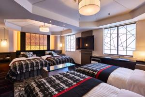 um quarto de hotel com três camas e uma televisão de ecrã plano em New Otani Inn Tokyo em Tóquio