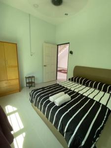 1 dormitorio con cama de rayas en blanco y negro en homestay kubang ikan chendering 5minit ke pantai, en Kuala Terengganu