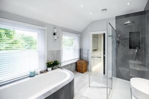 a bathroom with a tub and a shower and a sink at Dream House London with gym, cinema and housekeeper in Ealing