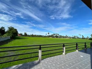 uma cerca em frente a um campo verde em ลานนา รีสอร์ท 