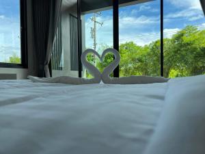 eine weiße Herzdekoration auf einem Bett mit Fenster in der Unterkunft ลานนา รีสอร์ท 