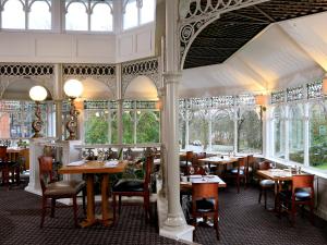 a restaurant with tables and chairs and windows at Macdonald Kilhey Court Hotel in Wigan