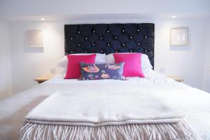 ein Schlafzimmer mit einem großen weißen Bett mit rosa Kissen in der Unterkunft 2 bed luxury duplex apartment in heart of Holt in Holt