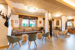 - un hall avec un canapé, des tables et des chaises dans l'établissement Monza Dolomites Hotel, à Moena