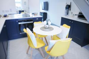 a kitchen with a white table and yellow chairs at 2 bed luxury duplex apartment in heart of Holt in Holt
