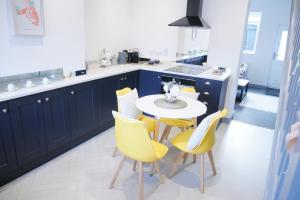 a kitchen with blue cabinets and a table and yellow chairs at 2 bed luxury duplex apartment in heart of Holt in Holt