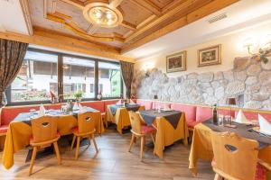 Monza Dolomites Hotel في موينا: مطعم بطاولات وكراسي وجدار حجري
