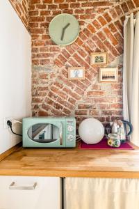 un forno a microonde su un bancone con un orologio su un muro di mattoni di Ripa Apartments Milano - Ripa 57 a Milano
