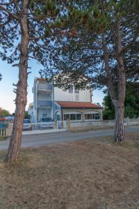 un bâtiment sur le côté d'une route avec deux arbres dans l'établissement Apartments Sunset -near Queen Beach, à Privlaka