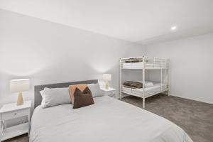 a white bedroom with a bed and a shelf at Aireys Sunset Beach House in Aireys Inlet