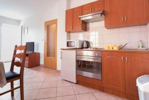 a kitchen with wooden cabinets and a stove top oven at Apartments Sunset near the sandy beach - by TA Leut Agency in Privlaka