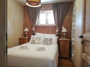 1 dormitorio con 1 cama blanca con 2 lámparas y una ventana en Domaine De Siane, en Plaine