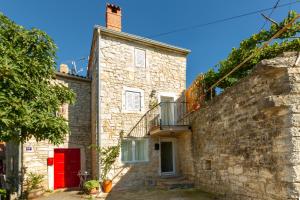 una casa de piedra con puerta roja y pared en Authentic Istrian Villa Stazione with Pool en Čabrunići