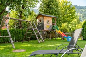 un parque infantil con una casa en el árbol y un tobogán en Appartementhaus Arzt, en Zell am See