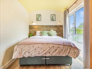 a bedroom with a large bed and a window at Ponsford Ponds - Goosedown Lodge in Cullompton