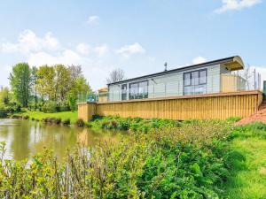 a house on a hill next to a river at Ponsford Ponds - Goosedown Lodge in Cullompton