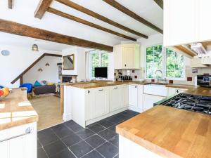 a large kitchen with white cabinets and a living room at Haven Cottage in Berrow