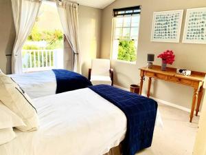 1 Schlafzimmer mit 2 Betten, einem Tisch und einem Fenster in der Unterkunft Bougainvillea House - The Heart of Simonstown in Simonʼs Town