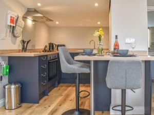 a kitchen with blue cabinets and a counter with two bar stools at Durcombe Water Annexe in Barbrook
