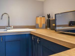 a kitchen with a counter with a sink and a tv at Durcombe Water Annexe in Barbrook