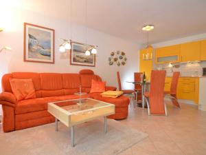 オストゼーバート・ゼリンにあるStrandwohnungen Sellin - WG02 mit Terrasseのリビングルーム(オレンジ色のソファ付)、キッチンが備わります。