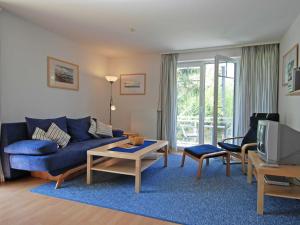 uma sala de estar com um sofá azul e uma televisão em Strandwohnungen Sellin - WG04 mit 2 Balkonen em Ostseebad Sellin
