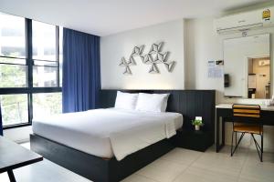 1 dormitorio con 1 cama grande, escritorio y ventana en 130 Hotel & Residence Bangkok, en Bangkok