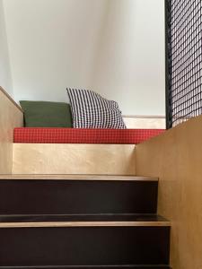 - un lit plateforme avec un oreiller rouge et vert dans l'établissement Isabella Living, à Maribor
