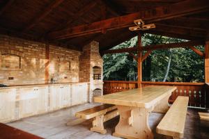 eine Außenküche mit einem Holztisch und Bänken in der Unterkunft Súgópatak Kulcsosház in Izvoare