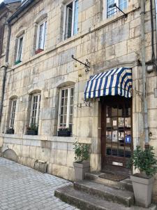 a building with a blue and white awning on it at Ancien Hôtel plein de charme in Baume-les-Dames