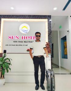 a man standing in front of a sign with a suitcase at SUN HOTEL in Hue
