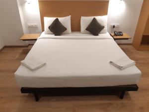 un grande letto bianco in una stanza con due tavoli di Alana Townhouse a Vijayawāda