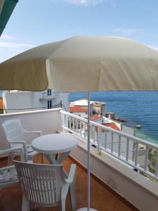 balcone con tavolo, sedie e ombrellone di Apartmani Jereb a Drasnice