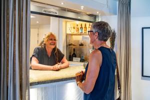 a woman standing at a counter talking to a woman at Hotell Breda Blick in Visby